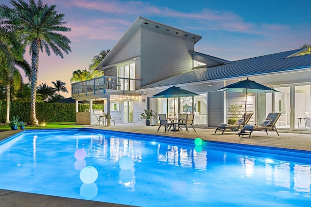 pool at dusk featuring an outdoor pool and a patio