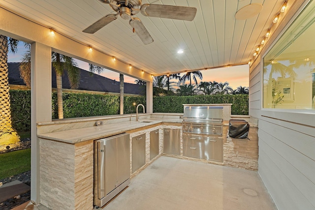 patio terrace at dusk featuring a grill, exterior kitchen, ceiling fan, and a sink