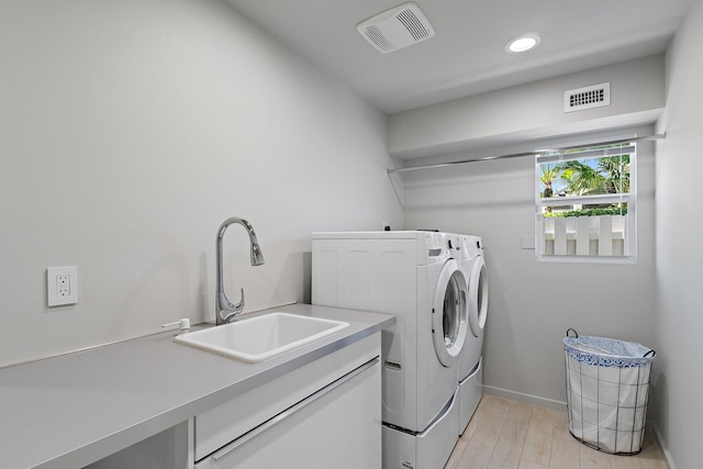 laundry area with a sink, laundry area, visible vents, and washing machine and clothes dryer