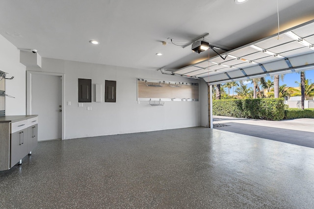 garage featuring electric panel, a garage door opener, and recessed lighting