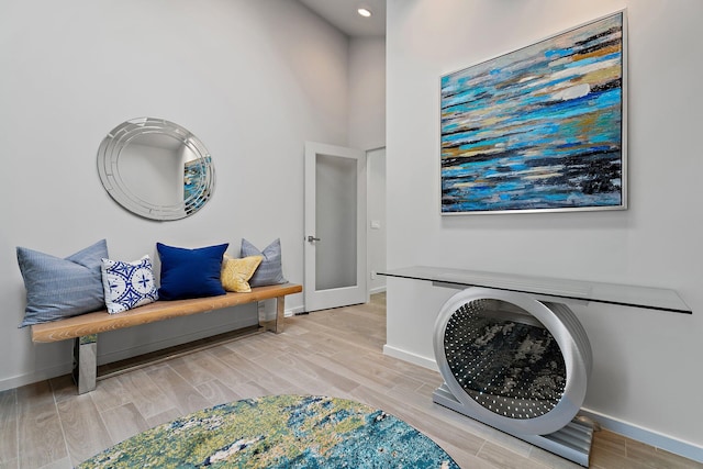 sitting room with baseboards, a high ceiling, and wood tiled floor