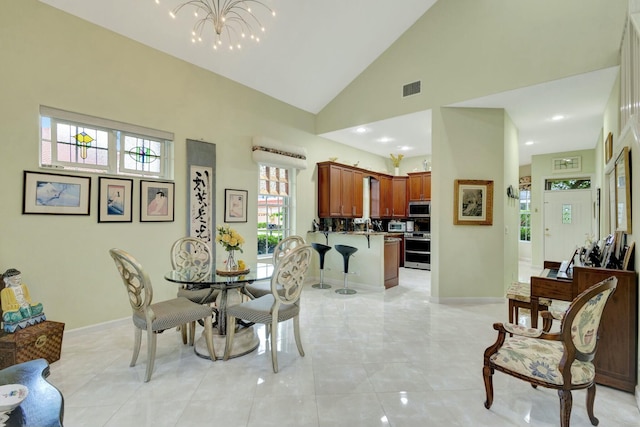 dining room with a notable chandelier, visible vents, high vaulted ceiling, and baseboards