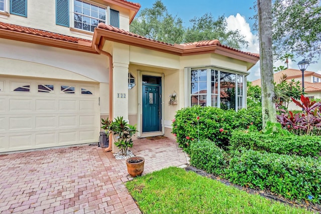 doorway to property with stucco siding, a tile roof, and decorative driveway