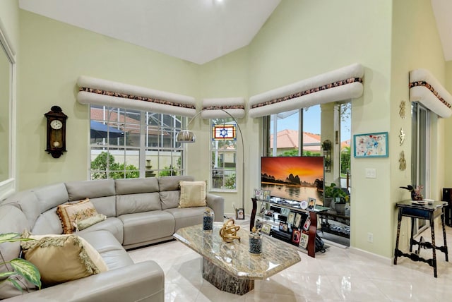 living area with baseboards, a towering ceiling, and tile patterned flooring