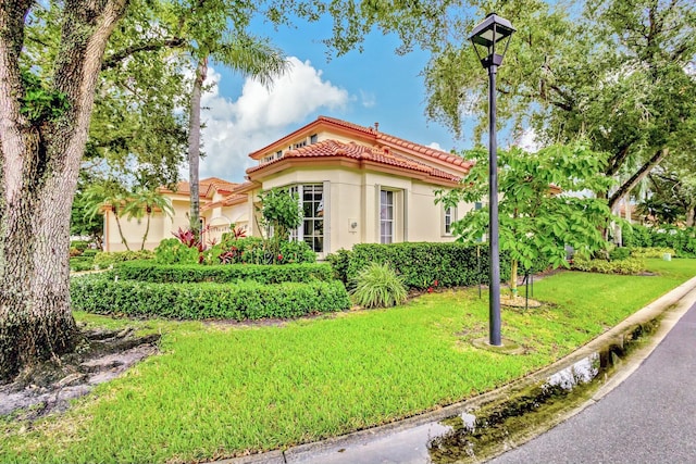 view of front of house with a front lawn, a tiled roof, and stucco siding