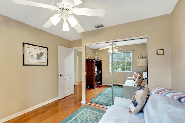 living room with a ceiling fan, wood finished floors, visible vents, and baseboards