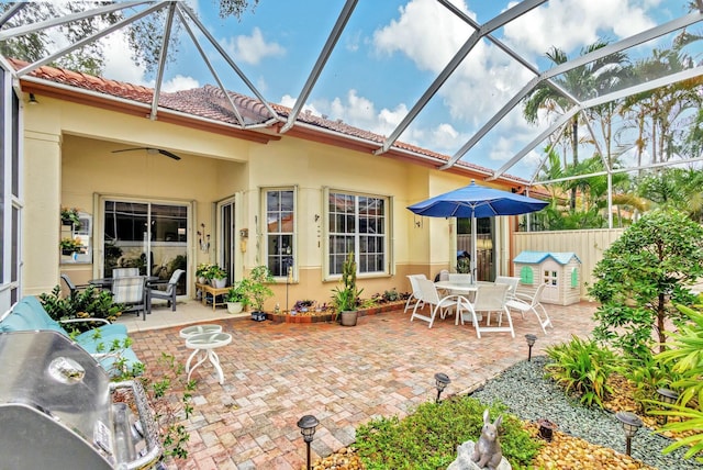 exterior space featuring glass enclosure, outdoor dining area, and a ceiling fan