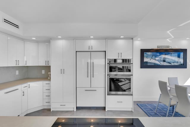 kitchen with visible vents, built in refrigerator, double oven, white cabinets, and light countertops