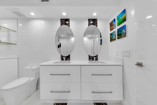 bathroom featuring double vanity, toilet, tile walls, and a sink