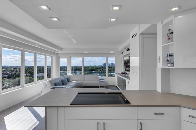 kitchen with black electric cooktop, plenty of natural light, open floor plan, and white cabinetry