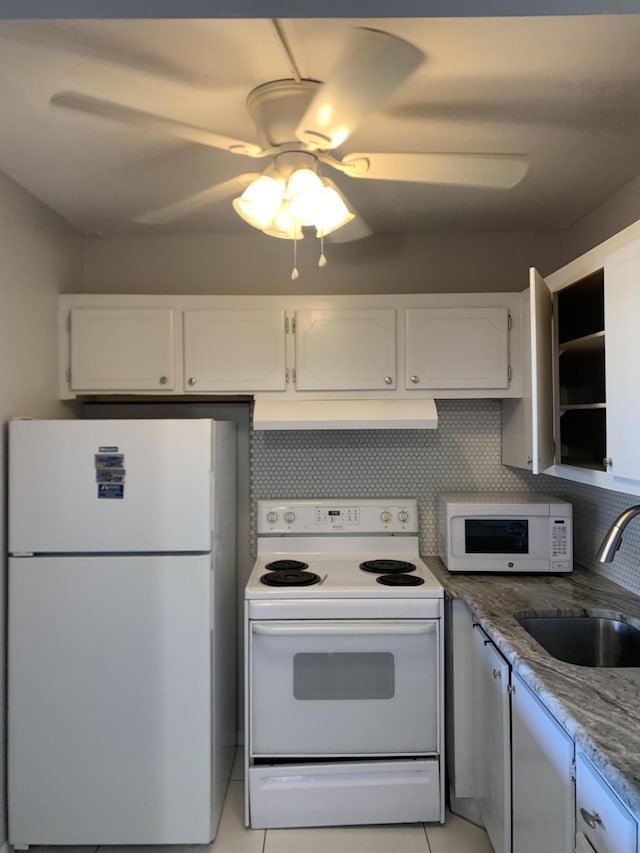 kitchen featuring white appliances, white cabinets, under cabinet range hood, and a sink