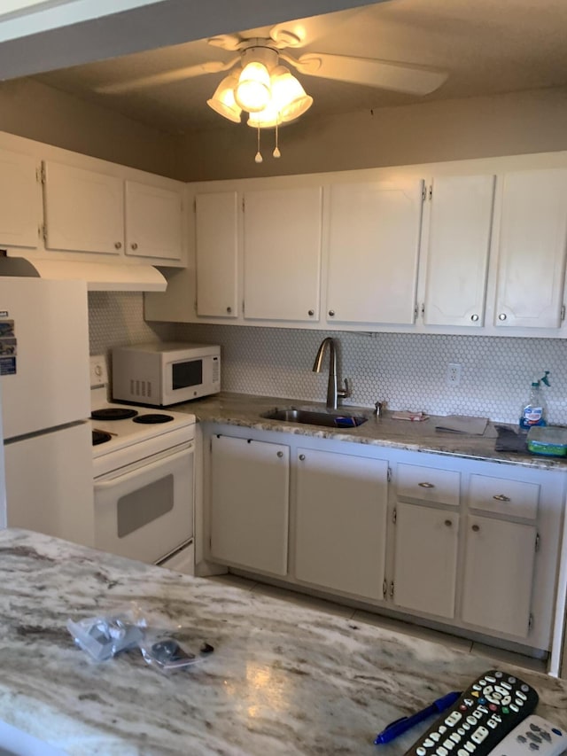 kitchen featuring white appliances, a ceiling fan, a sink, decorative backsplash, and white cabinets