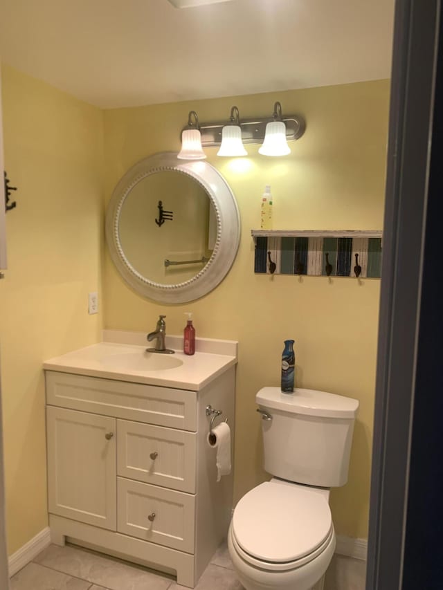 half bath with vanity, toilet, baseboards, and tile patterned flooring