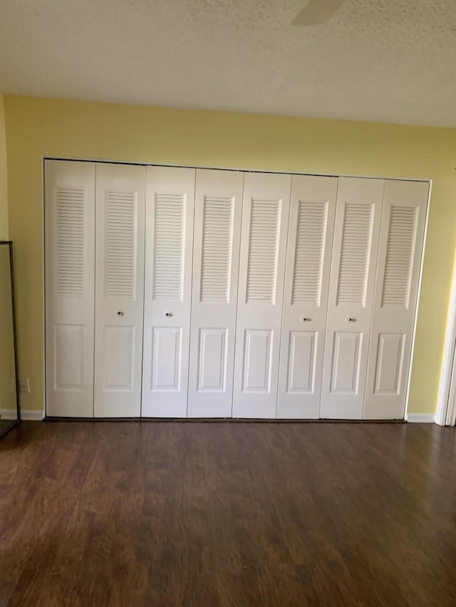 unfurnished bedroom featuring baseboards and dark wood-style flooring