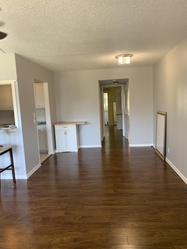 interior space with baseboards, a textured ceiling, and dark wood-style floors