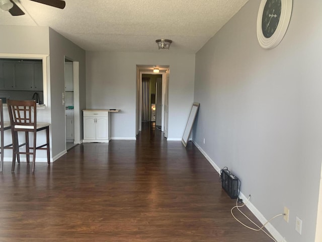 interior space featuring a textured ceiling, baseboards, and dark wood-style flooring