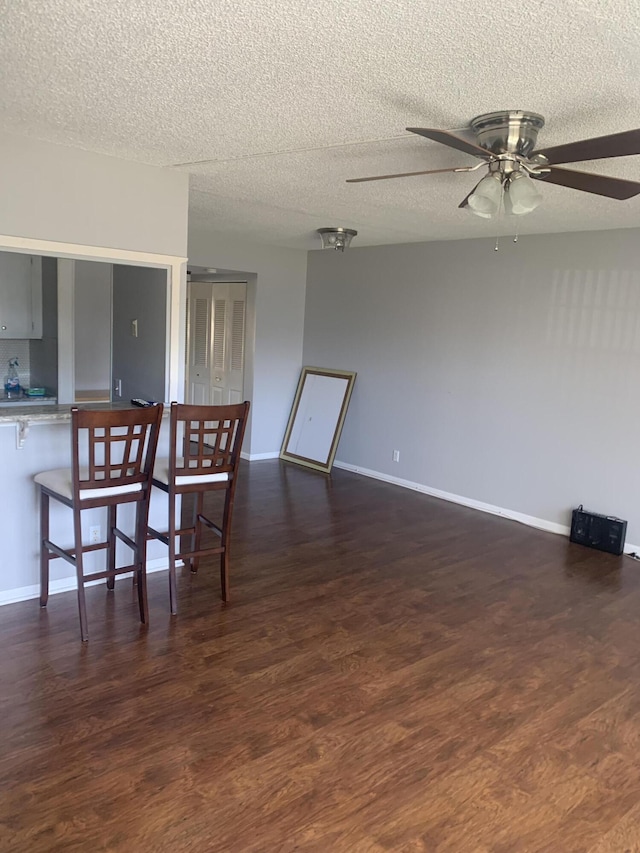 dining room featuring a ceiling fan, wood finished floors, baseboards, and a textured ceiling