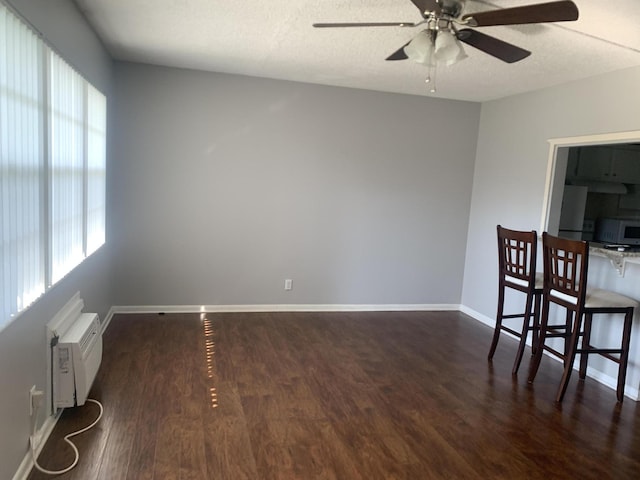 dining space with wood finished floors, baseboards, a wall mounted air conditioner, and a textured ceiling