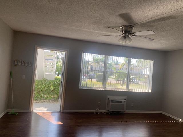 spare room with a ceiling fan, a wall mounted AC, baseboards, and wood finished floors