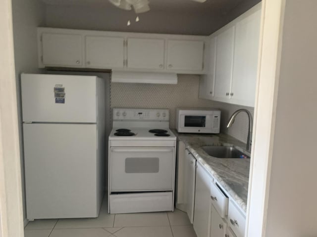 kitchen with light tile patterned floors, exhaust hood, white appliances, white cabinetry, and a sink