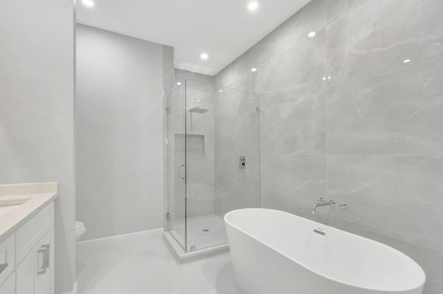 full bathroom with toilet, tile walls, a shower stall, a soaking tub, and vanity