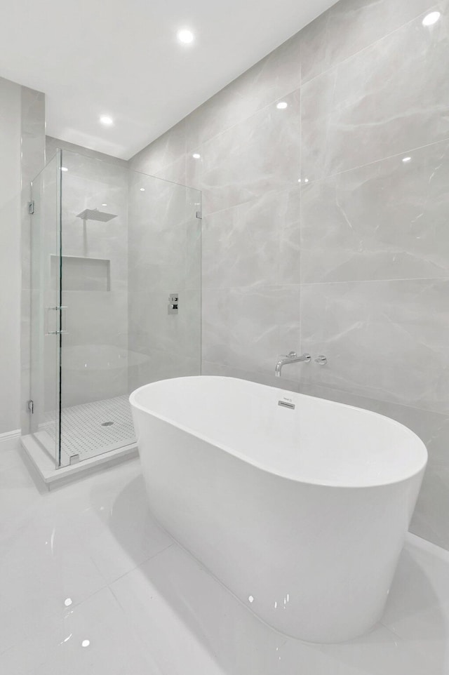 full bathroom with recessed lighting, a soaking tub, a shower stall, and tile walls