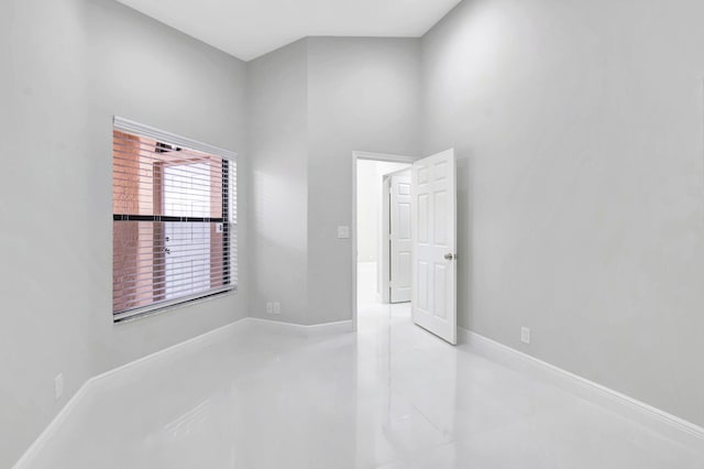 spare room featuring finished concrete flooring and baseboards