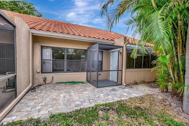 back of house with a tiled roof, a patio area, and stucco siding