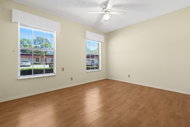 empty room featuring baseboards, a textured ceiling, a ceiling fan, and wood finished floors