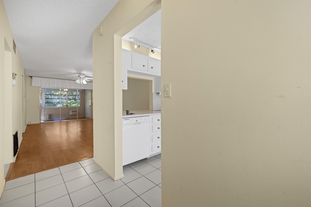 hall with light tile patterned floors, rail lighting, and a textured ceiling