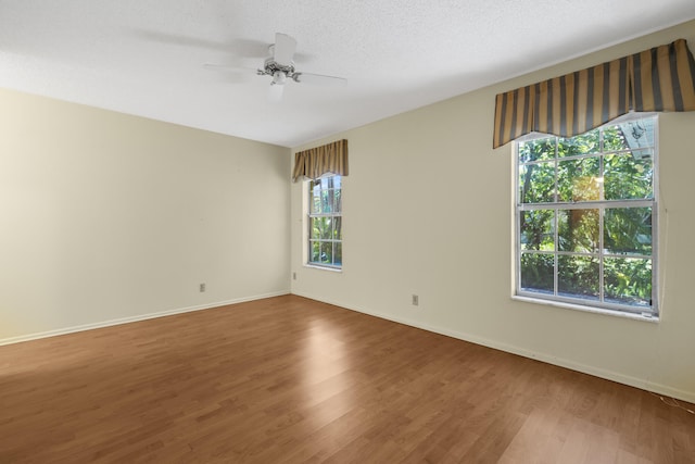 empty room with ceiling fan, baseboards, a textured ceiling, and wood finished floors