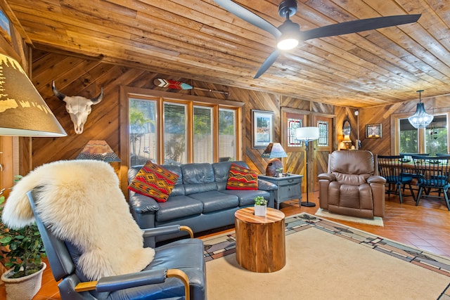 living area featuring wood ceiling, ceiling fan with notable chandelier, and wood walls