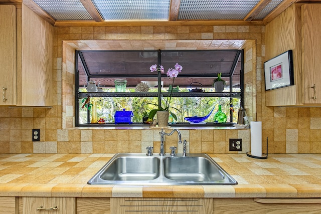 kitchen featuring a sink, tasteful backsplash, tile counters, and light brown cabinetry