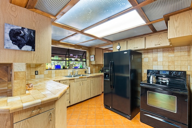 kitchen with light tile patterned flooring, light brown cabinetry, a sink, black appliances, and tasteful backsplash