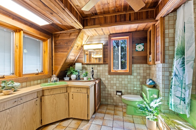 bathroom with wood ceiling, toilet, vanity, and a wealth of natural light