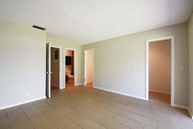 spare room with light tile patterned floors, baseboards, visible vents, and a textured ceiling