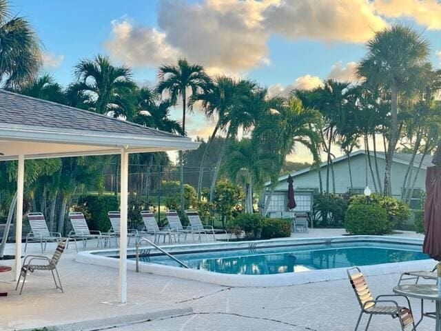 community pool with a patio area and fence