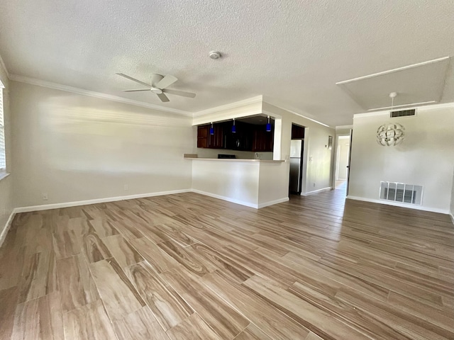 unfurnished living room featuring crown molding, wood finished floors, visible vents, and ceiling fan