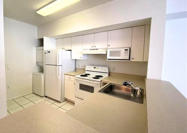 kitchen with under cabinet range hood, light countertops, light tile patterned floors, white appliances, and a sink