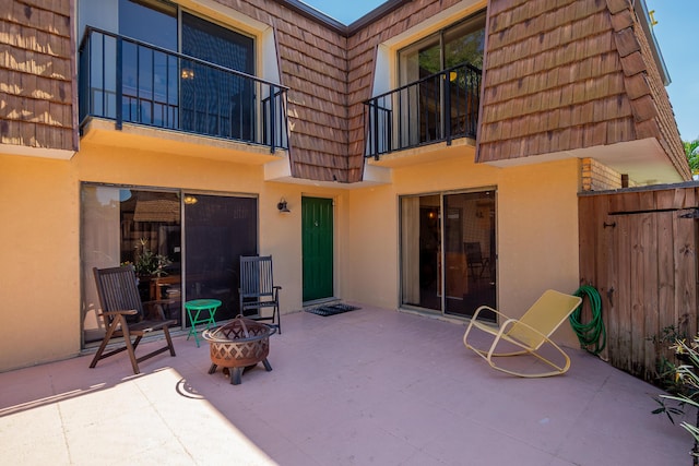 view of patio / terrace with a balcony, fence, and an outdoor fire pit