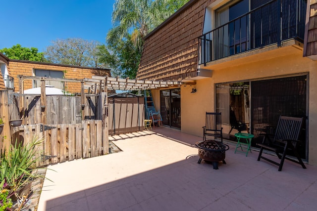 view of patio / terrace featuring an outdoor structure, fence, a shed, and an outdoor fire pit