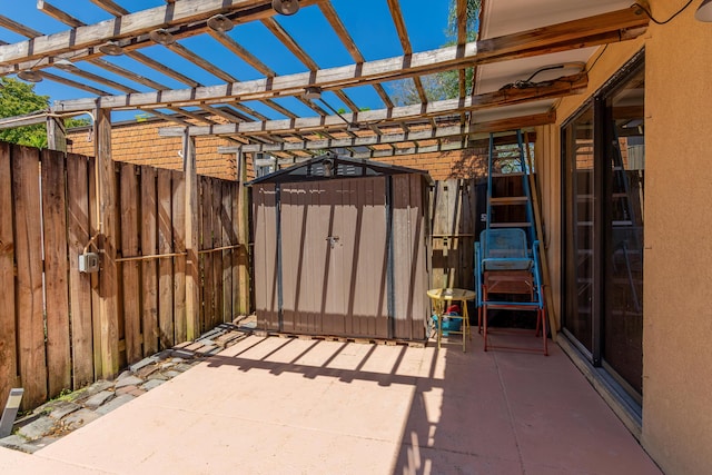 view of patio with an outbuilding, a storage shed, a pergola, and fence