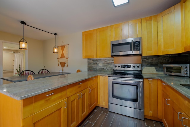 kitchen featuring light stone countertops, a peninsula, a toaster, stainless steel appliances, and decorative backsplash