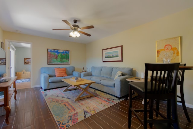 living area with baseboards, a ceiling fan, and wood tiled floor