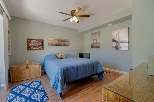 bedroom featuring baseboards, wood finished floors, and a ceiling fan