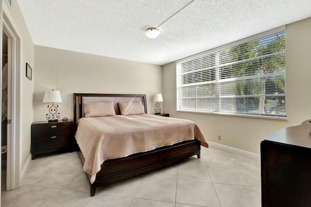 bedroom with light tile patterned floors, a textured ceiling, and baseboards