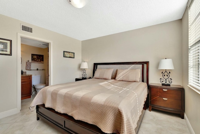 bedroom featuring light tile patterned flooring, baseboards, visible vents, and a textured ceiling