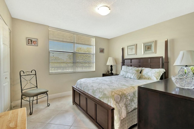 bedroom featuring light tile patterned floors, baseboards, and a textured ceiling