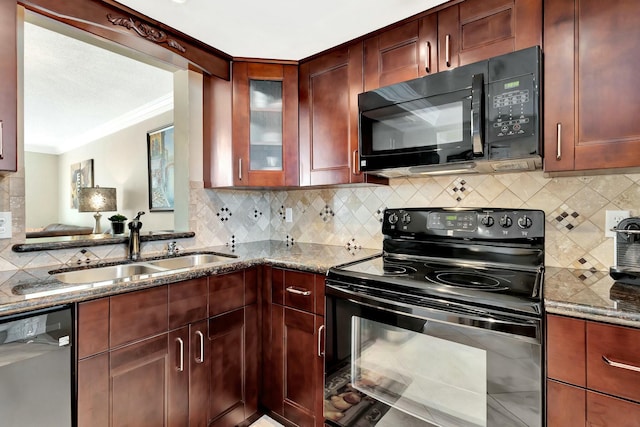 kitchen with reddish brown cabinets, dark stone countertops, black appliances, and a sink