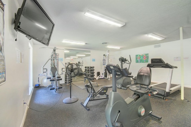 gym with visible vents, baseboards, and a textured ceiling